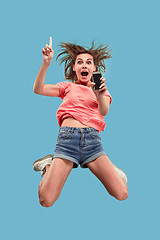 Image showing Full length of pretty young woman with mobile phone while jumping