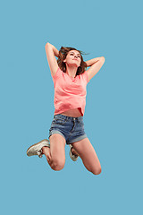 Image showing Freedom in moving. Pretty young woman jumping against blue background