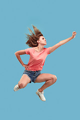 Image showing Freedom in moving. Pretty young woman jumping against blue background