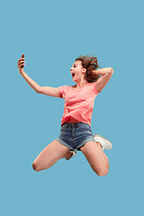 Image showing Full length of pretty young woman with mobile phone while jumping