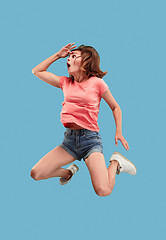 Image showing Freedom in moving. Pretty young woman jumping against blue background