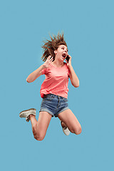 Image showing Full length of pretty young woman with mobile phone while jumping