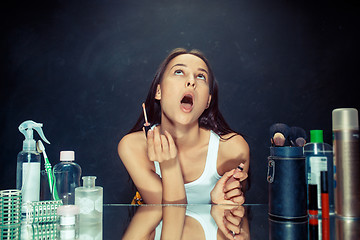 Image showing Beauty woman applying makeup. Beautiful girl looking in the mirror and applying cosmetic with a brush.