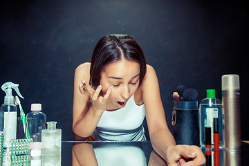 Image showing Beauty woman applying makeup. Beautiful girl looking in the mirror and applying cosmetic with a Eyeliner.