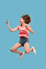 Image showing Full length of pretty young woman with mobile phone while jumping