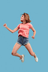 Image showing Freedom in moving. Pretty young woman jumping against blue background