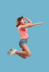 Image showing Freedom in moving. Pretty young woman jumping against blue background