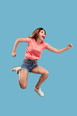 Image showing Freedom in moving. Pretty young woman jumping against blue background