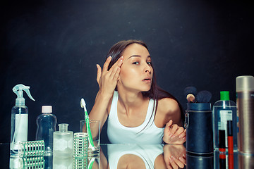 Image showing Unsatisfied young woman looking at her self in mirror on black background