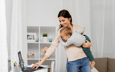 Image showing happy mother with baby and laptop working at home