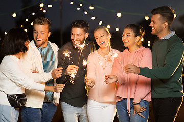 Image showing happy friends with sparklers at rooftop party