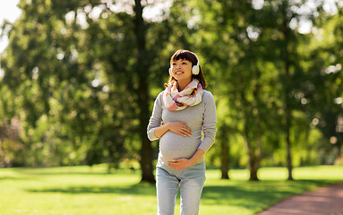 Image showing happy pregnant asian woman in headphones at park