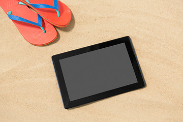 Image showing tablet computer and flip flops on beach sand