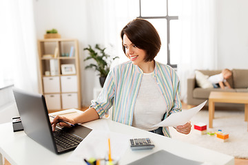 Image showing mother working at laptop and baby boy at home