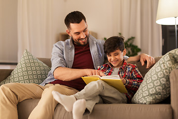 Image showing happy father and son reading book sofa at home