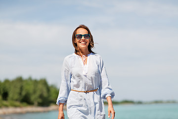 Image showing happy smiling woman walking along summer beach