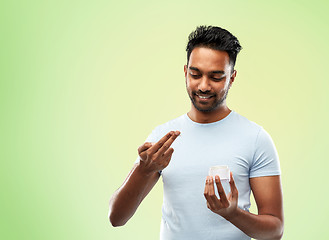 Image showing happy indian man applying cream to face