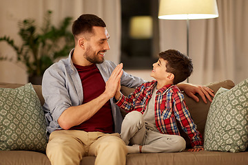 Image showing father and son making high five at home in evening
