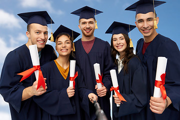 Image showing happy graduates with diplomas taking selfie