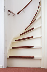 Image showing White wooden stairs with red mats