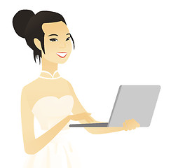 Image showing Young asian bride in a white dress using a laptop.