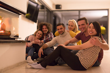 Image showing multiethnic couples sitting in front of fireplace