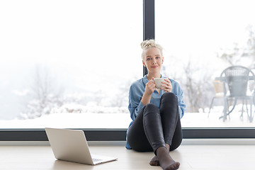 Image showing woman drinking coffee and using laptop at home