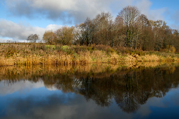 Image showing Autumn landscape with colorful trees, yellow grass and river.