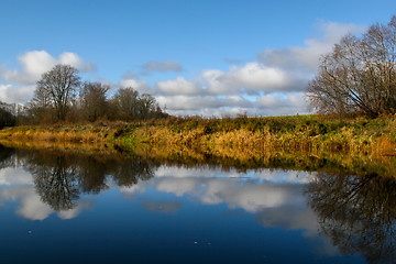 Image showing Autumn landscape with colorful trees, yellow grass and river. Re