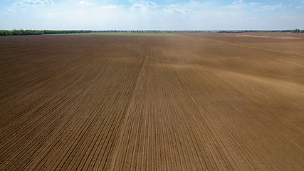 Image showing Agricultural ploughed field and soil in spring against the blue sky. Photo from the drone