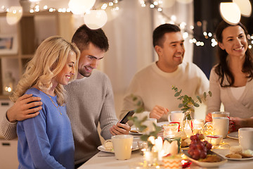 Image showing happy friends with smartphone at tea party at home