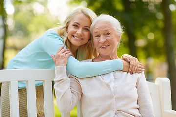 Image showing daughter with senior mother hugging on park bench