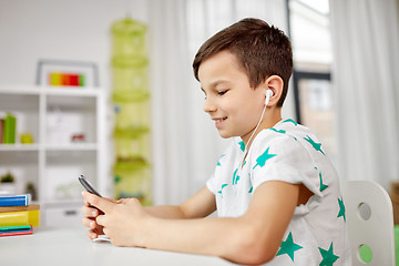 Image showing boy in earphones listening to music on smartphone