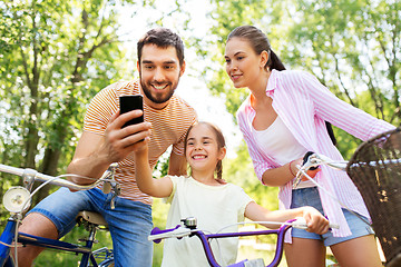 Image showing family with smartphone and bicycles in summer park