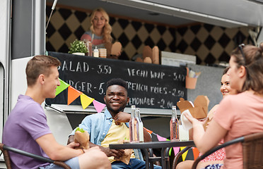 Image showing happy friends with drinks eating at food truck