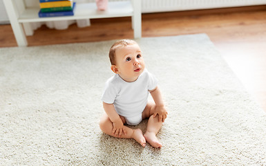 Image showing baby sitting on floor at home and looking up