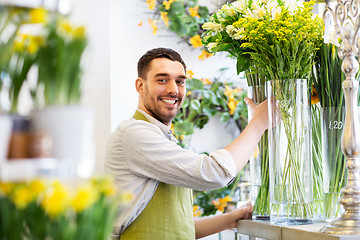Image showing happy florist man setting flowers at flower shop