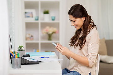 Image showing woman with papers and smartphone working at home