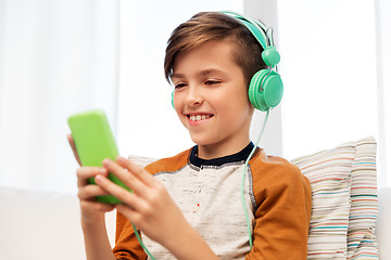 Image showing happy boy with smartphone and headphones at home