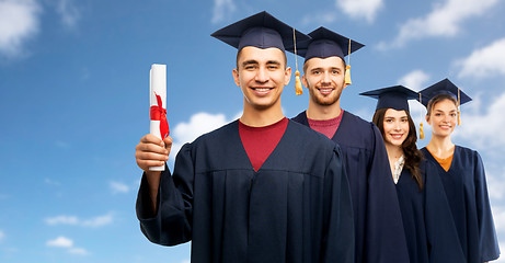 Image showing graduates in mortar boards with diploma