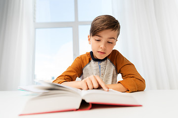 Image showing student boy reading book at home table