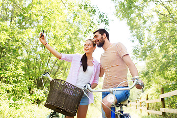 Image showing couple with bicycles taking selfie by smartphone