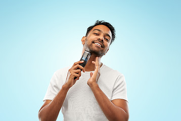 Image showing smiling indian man shaving beard with trimmer