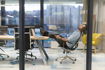 Image showing young businessman relaxing at the desk