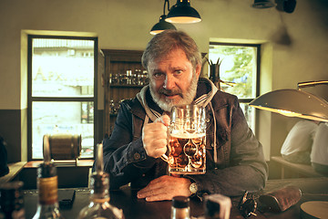 Image showing The senior bearded male drinking beer in pub