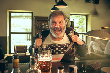 Image showing The senior bearded male drinking beer in pub