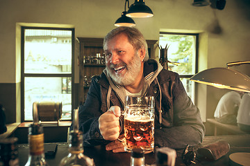 Image showing The senior bearded male drinking beer in pub