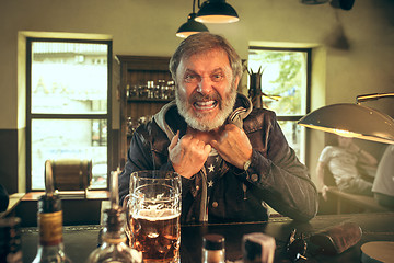 Image showing The senior bearded male drinking beer in pub