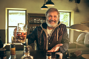 Image showing The senior bearded male drinking beer in pub