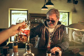 Image showing The senior bearded male drinking beer in pub